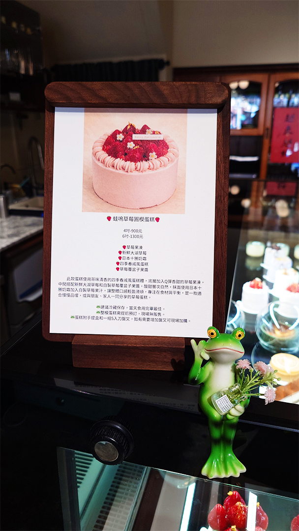 蛙鳴圓模蛋糕菜單，以木板製作，旁邊有青蛙捧花裝飾