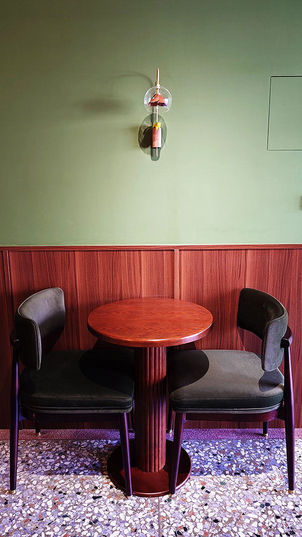 蛙鳴甜點靠牆座位，木質桌與深綠絨布座椅